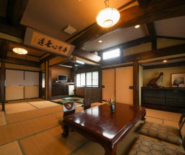 Tatami room with low wooden table, cushions and exposed beams at Iroriyado Hidaya in Gifu, Chūbu