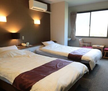 Twin beds with bedside lamps and window seating at Iruka Onsen Hotel Seiryuusou in Mie, Kansai