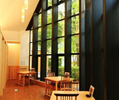 Spacious dining area with tall grid windows and wooden tables at Iruka Onsen Hotel Seiryuusou in Mie, Kansai