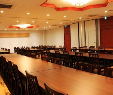 Spacious banquet hall with long wooden tables and chairs at Iruka Onsen Hotel Seiryuusou Mie Kansai