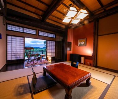 Traditional tatami room with low table and balcony overlooking mountains at Isamikan in Tochigi