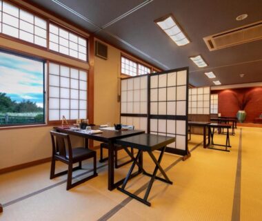Low-table tatami dining area with shoji screens and window overlooking greenery at Isamikan, Tochigi