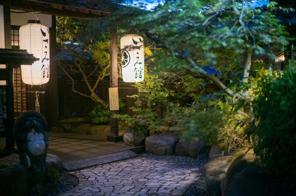 Lantern-lit ryokan entrance Isamikan Tochigi Lantern-lit stone path leading to Isamikan entrance in Tochigi, surrounded by trees and traditional lanterns