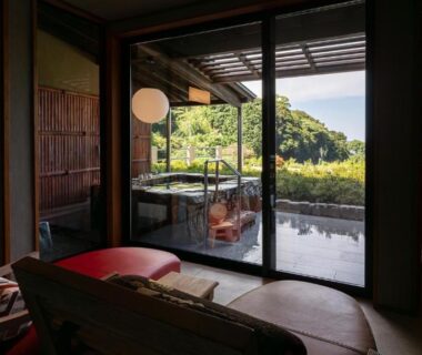 Tatami room with sliding doors opening to an outdoor wooden bath and green hillside view at Isaribi, Shizuoka