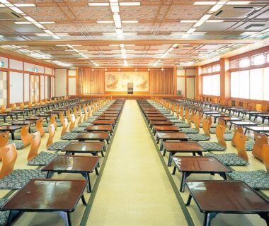Tatami banquet room at Isawa View Hotel in Yamanashi with rows of low tables and wooden backrest chairs