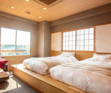 Room with raised wooden platform beds, shoji screen, lounge chair and large window at Ise-Shima Ohtaya in Mie