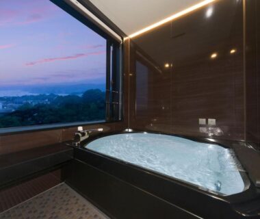 Indoor bathtub with large window overlooking distant landscape at dusk, Ise-Shima Ohtaya, Mie