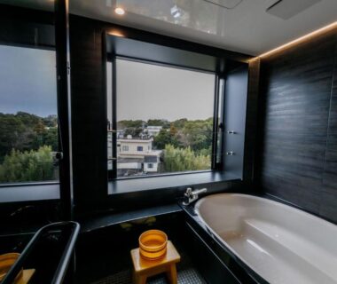 Bathtub and wooden stools by large windows overlooking greenery at Ise-Shima Ohtaya in Mie, Kansai