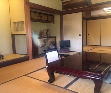 Tatami mats with low lacquered table, shoji screens, sliding doors, alcove decorations and small television at Ise Todaya Ryoan Mie