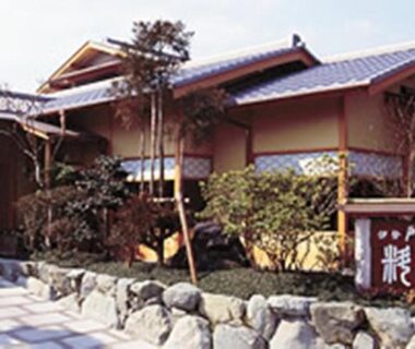 Wooden facade, stone path and shrubs at Ise Todaya Ryoan entrance in Mie, Kansai