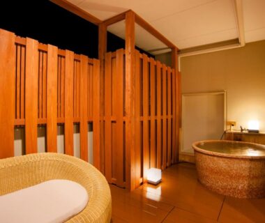 Indoor round soaking tub, wicker chair, wooden slatted divider in ryokan bathing room at Isegekusando Iseshinsen, Mie