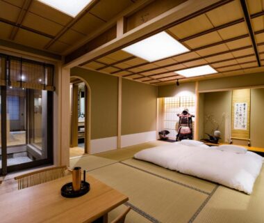 Traditional tatami room with futon, low table, shoji screens and sliding glass door at Ishibekoji Muan Kyoto
