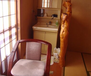 Interior tatami room with shoji screens, wooden post and chair at Ishibu-so in Shizuoka