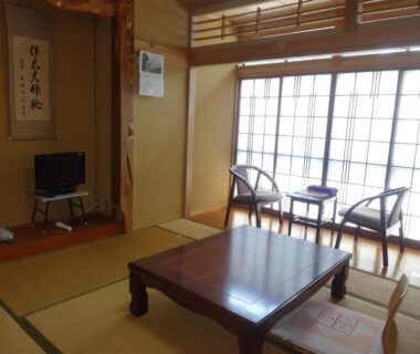 Tatami room with low table, shoji screens and seating at Ishibu-so in Shizuoka, Chūbu