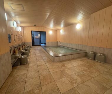 Tiled indoor bath with washing stations, stools and faucets at Ishicho ryokan in Kyoto