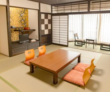 Traditional tatami room with low wooden table, zabuton cushions, shoji screens and seating area at Ishicho in Kyoto