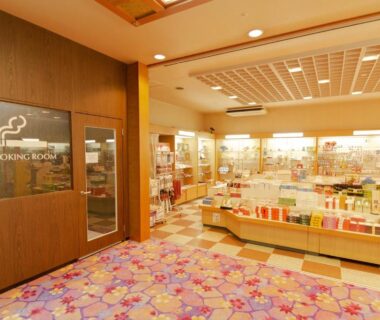 Gift shop interior with colorful shelves, patterned carpet, and smoking room door at Ishicho ryokan, Kyoto
