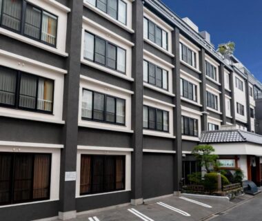 Multi-story exterior with entrance canopy and parking at Ishicho Ryokan in Kyoto