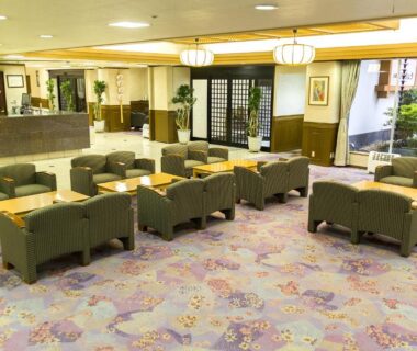 Spacious ryokan lobby with upholstered seating, reception desk, shoji screen and indoor garden view