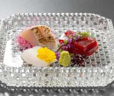 Delicate sashimi and edible flowers on crystal plate at Ishinoya Atami, Shizuoka