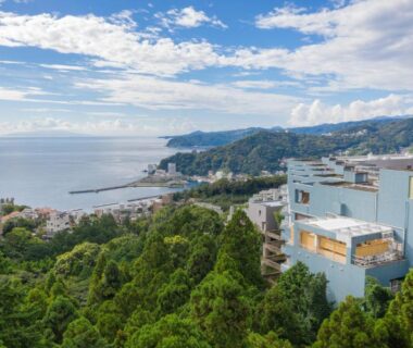 White hillside ryokan building with terraces overlooking ocean and Atami coastal town in Shizuoka