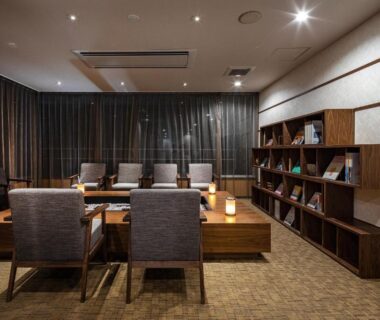 Cozy ryokan lounge with low tables, armchairs and bookshelf at Ishinoya Atami in Shizuoka