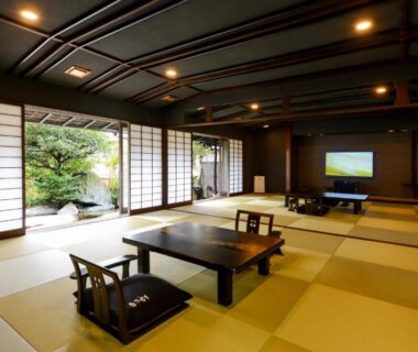 Spacious tatami room with low tables, zaisu chairs and shoji screens overlooking a small courtyard garden