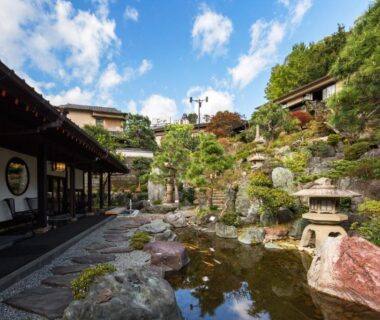 Traditional ryokan garden with pond, stone lantern and wooden buildings at Ishinoya Izunagaoka, Shizuoka