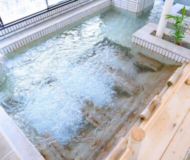 Bubbling indoor onsen bath with wooden ledge at Issinkan in Tochigi, Kantō