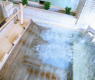 Indoor onsen bath with bubbling water, tiled steps and wooden spout at Issinkan, Tochigi