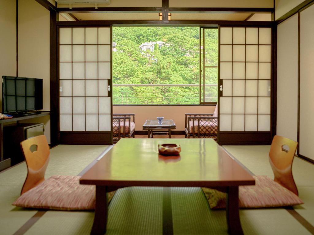 Tatami Room at Issinkan Tochigi Tatami room with low table, shoji screens and veranda overlooking green foliage at Issinkan, Tochigi, Kantō, Japan