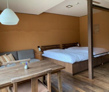 Wood-floored twin room with low table and sofa at Itamuro Onsen Daikokuya Tochigi