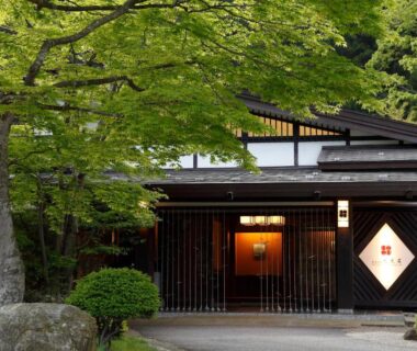 Facade with wooden lattice, lantern-lit doorway and surrounding trees at Itamuro Onsen Daikokuya, Tochigi prefecture
