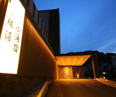 Evening view of a lit ryokan entrance with vertical signage and covered driveway at Ito Kowakien in Shizuoka