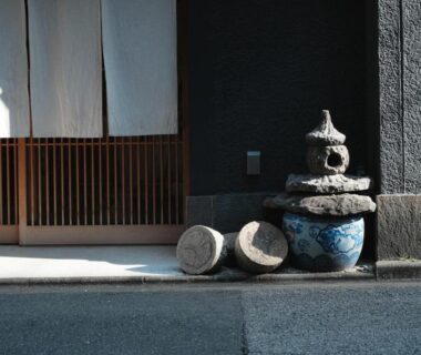 Stone lantern beside ceramic pots at Ito Ryokan entrance with wooden sliding door in Tokyo, Kantō
