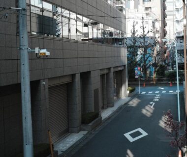Narrow Tokyo side street with concrete buildings and overhead utility lines near Ito Ryokan