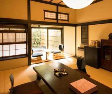 Tatami room with low table, shoji screens and small garden view at Ito Ryokuyu, Shizuoka