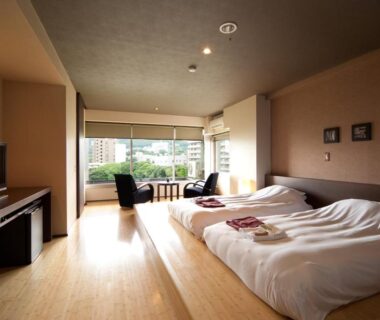 Spacious twin room with low beds, seating area and city view at Ito Yukitei in Shizuoka