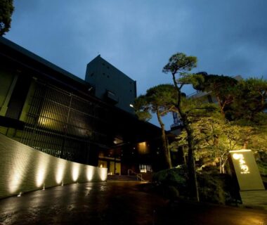 Illuminated entrance and pathway with traditional facade and sculpted pine at Ito Yukitei in Shizuoka