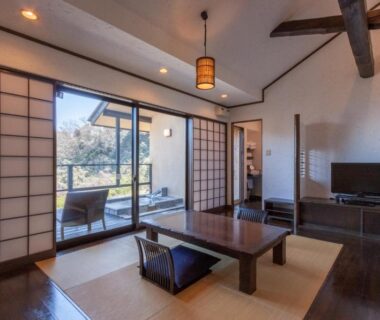 Tatami room with low table, shoji screens, balcony seating and greenery at Ito Yukitei Kawana Bettei, Shizuoka