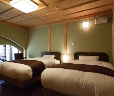 Twin beds, shoji screens and seating by window at Ito Yukitei Kawana Bettei, Shizuoka, Chūbu Japan