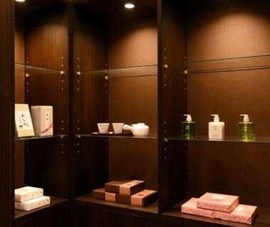 Wooden display shelves with toiletries, soaps and bottles under warm lighting at Ito Yukitei Kawana Bettei, Shizuoka