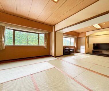 Spacious tatami room with seating area, TV and large windows at Itoen Hotel Hakone Yumoto, Kanagawa
