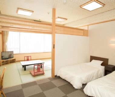 Tatami seating area and twin Western beds with low table and partial room divider at Itoen Hotel Iizakakanouya, Fukushima