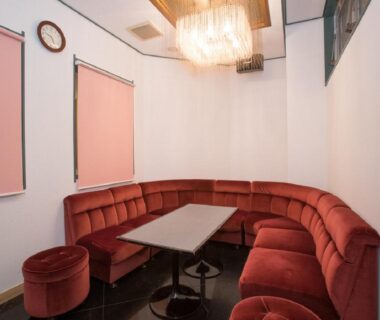 Curved red velvet banquette with table and chandelier at Itoen Hotel Iizakakanouya, Fukushima