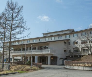 Multi-story ryokan exterior with entrance, balconies and bare trees at Itoen Hotel Kusatsu in Gunma
