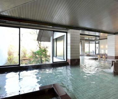 Spacious indoor communal bath with large windows overlooking a landscaped garden at Itoen Hotel New Sakura, Tochigi