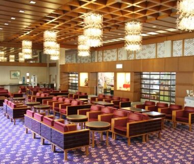 Spacious lobby with red upholstered seating, chandeliers and patterned carpet at Itoen Hotel New Sakura in Tochigi