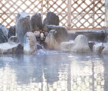 Rock-edged steaming onsen bath with lattice screen at Itoen Hotel Shiobara, Tochigi