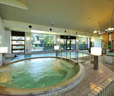 Tiled circular indoor onsen bath with large windows and garden view at Itoen Hotel Shiobara, Tochigi